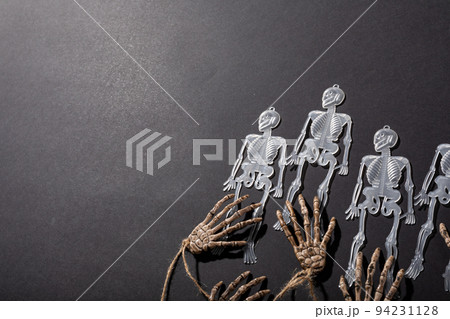 Multiple skeleton toys and skeleton hands with copy space on grey background 94231128