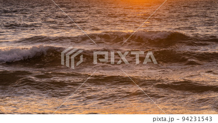Close-up of ocean waves washing beach at sunrise 94231543