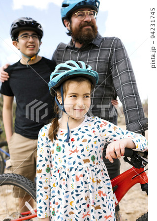 Father with children (8-9, 14-15) wearing bike helmets 94231745