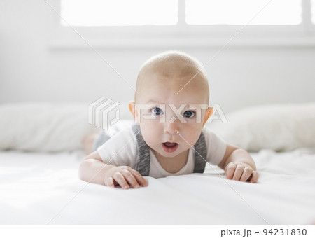 Portrait of baby boy (6-11 months) lying on bed Portrait of baby boy (6-11 months) lying on bed 94231830