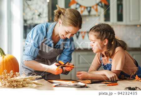 Happy smiling family mother and daughter making Halloween home decorations together 94232435