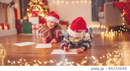 Children lying on the floor indoors and writing letters for Santa Claus. Children lying on the floor indoors and writing letters for Santa Claus. 94233049