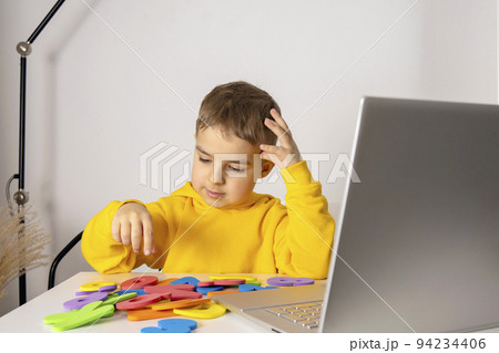 Adorable, cute, little boy learning alphabet online, with laptop at home. Child using e-learning platform to make a video call with his teacher and study. Homeschooling and distance education for kids 94234406