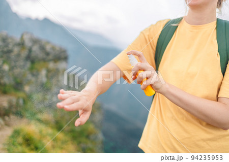 Woman applying insect repellent against mosquito and tick on her hand during hike in nature top mountain. Skin protection against insect bite  94235953