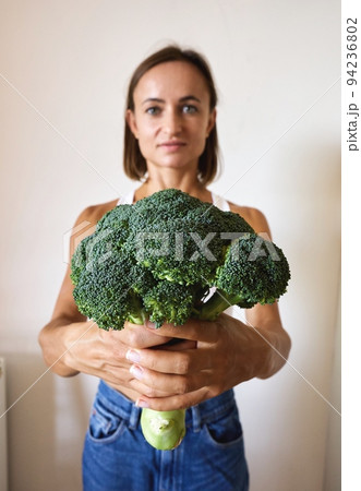 young woman dressed in white t-shirt showing with broccoli 94236802