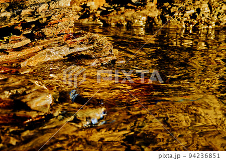 Layered section of rocky red stone and clear clear water 94236851