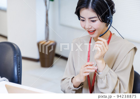 オフィスでヘッドセットをつけて仕事をする若い女性 オフィスでヘッドセットをつけて仕事をする若い女性 94238875