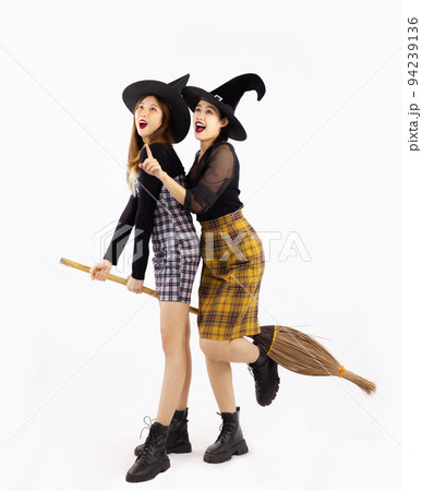 Halloween concept, young asian women wearing witch hat holding broom and shopping bags posing on white background. Halloween concept, young asian women wearing witch hat holding broom and shopping bags posing on white background. 94239136