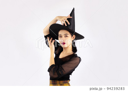 Young asian woman in black halloween costume wearing witch hat posing on white background. Young asian woman in black halloween costume wearing witch hat posing on white background. 94239283