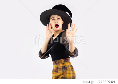 Young asian woman in halloween costume wearing witch hat posing scary on white background. Young asian woman in halloween costume wearing witch hat posing scary on white background. 94239284