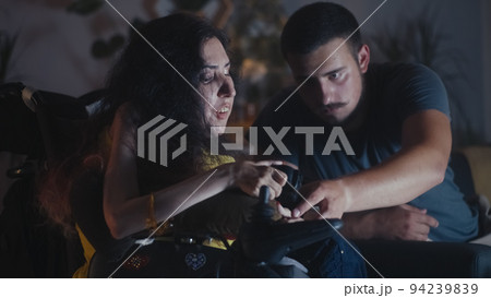 Man playing video game near woman in wheelchair 94239839