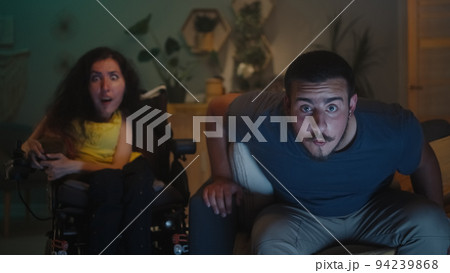 Woman with disability and man watching TV Woman with disability and man watching TV 94239868