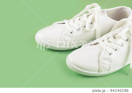 White sneakers on green background. copy space. White sneakers on green background. copy space. 94240286
