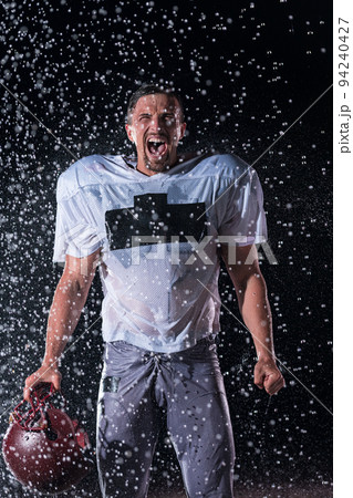 American Football Field: Lonely Athlete Warrior Standing on a Field Holds his Helmet and Ready to Play. Player Preparing to Run, Attack and Score Touchdown. Rainy Night with Dramatic Fog, Blue Light American Football Field: Lonely Athlete Warrior Standing on a Field Holds his Helmet and Ready to Play. Player Preparing to Run, Attack and Score Touchdown. Rainy Night with Dramatic Fog, Blue Light 94240427