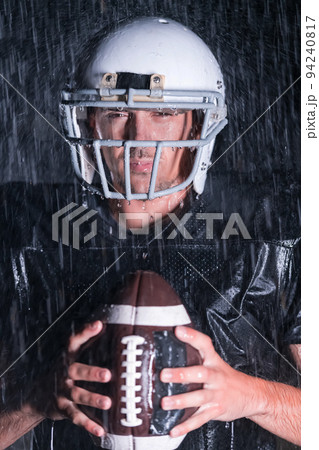 American Football Field: Lonely Athlete Warrior Standing on a Field Holds his Helmet and Ready to Play. Player Preparing to Run, Attack and Score Touchdown. Rainy Night with Dramatic Fog, Blue Light American Football Field: Lonely Athlete Warrior Standing on a Field Holds his Helmet and Ready to Play. Player Preparing to Run, Attack and Score Touchdown. Rainy Night with Dramatic Fog, Blue Light 94240817