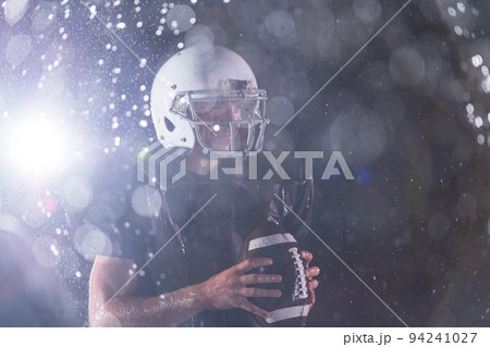 American Football Field: Lonely Athlete Warrior Standing on a Field Holds his Helmet and Ready to Play. Player Preparing to Run, Attack and Score Touchdown. Rainy Night with Dramatic Fog, Blue Light American Football Field: Lonely Athlete Warrior Standing on a Field Holds his Helmet and Ready to Play. Player Preparing to Run, Attack and Score Touchdown. Rainy Night with Dramatic Fog, Blue Light 94241027