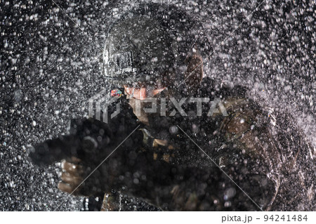 Army soldier in Combat Uniforms with an assault rifle, plate carrier and combat helmet going on a dangerous mission on a rainy night. Army soldier in Combat Uniforms with an assault rifle, plate carrier and combat helmet going on a dangerous mission on a rainy night. 94241484