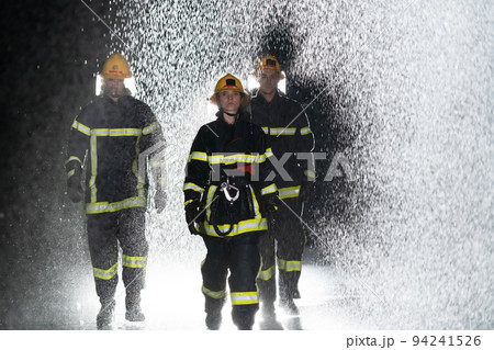 Portrait of a group of firefighters standing and walking brave and optimistic with a female as team leader. Portrait of a group of firefighters standing and walking brave and optimistic with a female as team leader. 94241526