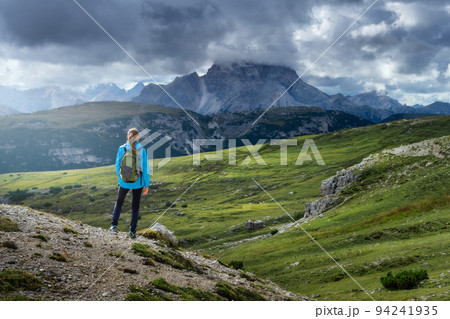 Girl with backpack on the hill looking at mountains at sunset 94241935