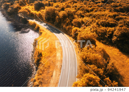 Aerial view of road near blue sea, forest at sunset in autumn 94241947