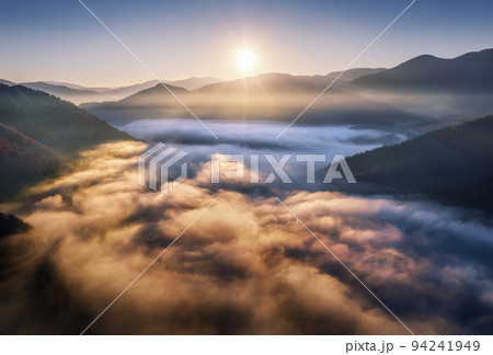 Mountains in low clouds at sunrise in summer. Aerial view 94241949