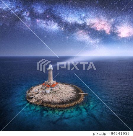 Lighthouse on smal island in the sea and Milky Way at night 94241955