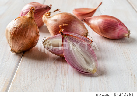 Halved red eschalot and whole bulbs on a white wooden table. Halved red eschalot and whole bulbs on a white wooden table. 94243263