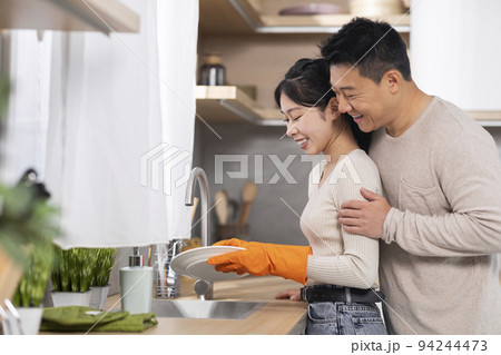 Loving korean husband supporting wife while she is washing dishes Loving korean husband supporting wife while she is washing dishes 94244473