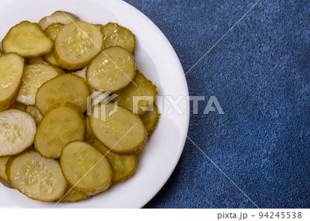 Delicious salted, canned cucumbers cut into slices on a white ceramic plate 94245538