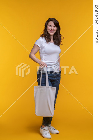 Woman smiling at camera showing shopping bag Woman smiling at camera showing shopping bag 94245990