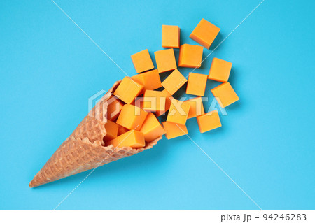 Waffle Cone with Yellow Cheese Cubes on blue background 94246283