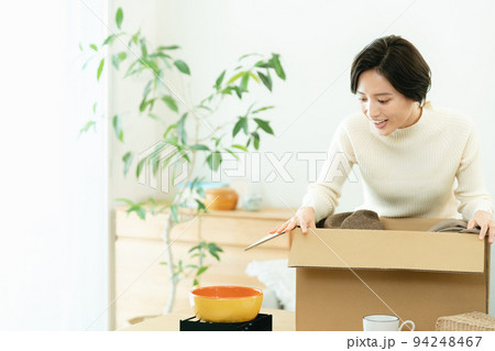 リビングで荷物を梱包する女性 リビングで荷物を梱包する女性 94248467