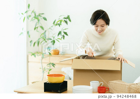 リビングで荷物を梱包する女性 リビングで荷物を梱包する女性 94248468