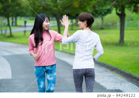 ジョギング中にハイタッチする二人の女性 94249122