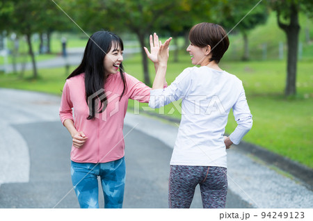 ジョギング中にハイタッチする二人の女性 94249123