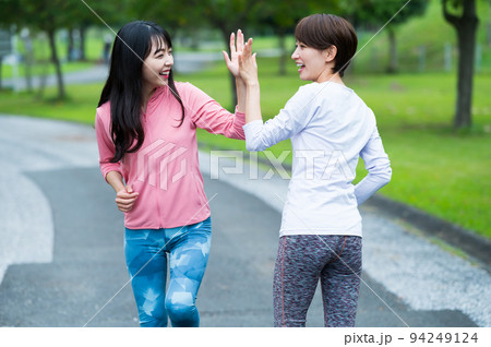 ジョギング中にハイタッチする二人の女性 94249124