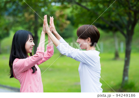 ハイタッチする二人の女性 94249186