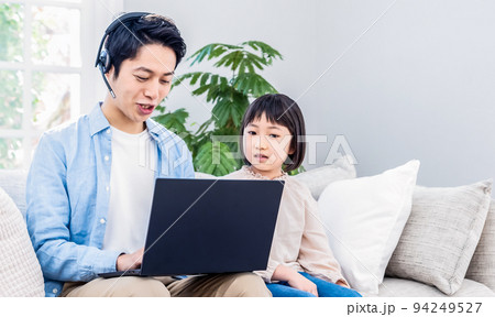 ソファに座ってノートパソコンで仕事をするパパと話しかける子供 94249527