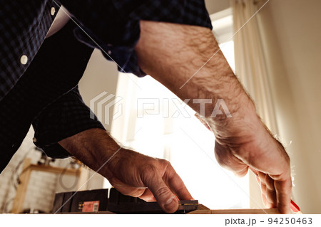 Carpenter makes pencil marks on a wood plank Carpenter makes pencil marks on a wood plank 94250463