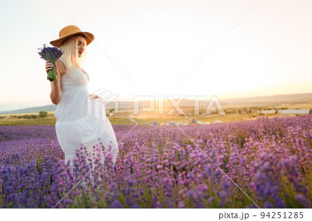 Young woman in long white dress standing in lavender field 94251285