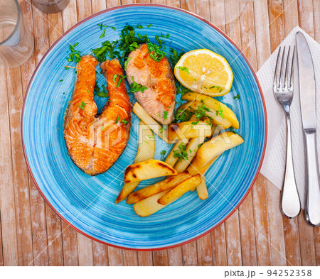 Portion of just cooked grilled salmon steak with fried potato 94252358