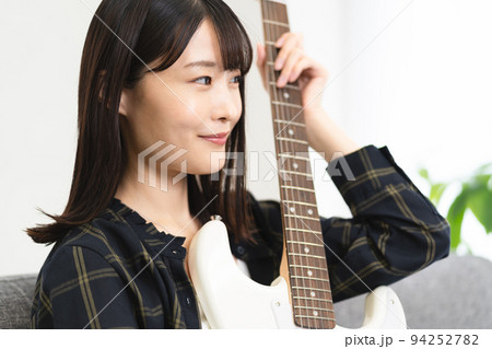 ソファに座りギターを弾く女性 ソファに座りギターを弾く女性 94252782