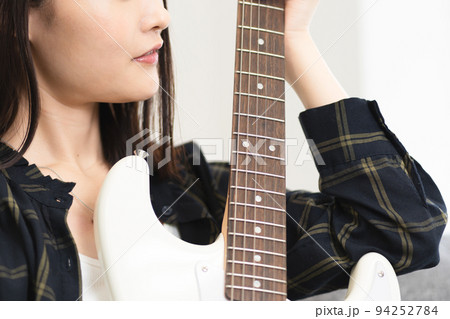 ソファに座りギターを弾く女性 ソファに座りギターを弾く女性 94252784