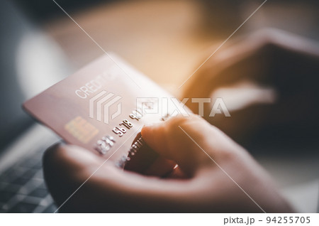 Close up hands holding credit card, typing on the keyboard of laptop, online shopping. 94255705