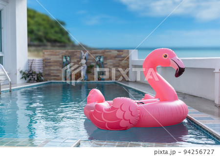 Pink inflatable flamingo on swimming pool. Concept for summer day Pink inflatable flamingo on swimming pool. Concept for summer day 94256727