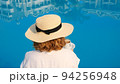 woman holds a white cup of coffee in her hands on the background of a blue swimming pool. Good 94256948