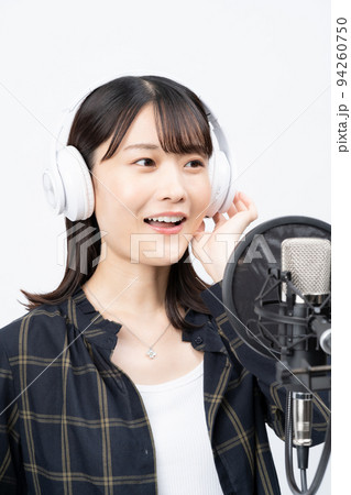 白いヘッドホンを付けて歌う若い女性 94260750