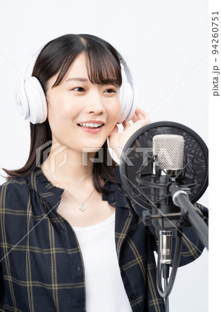 白いヘッドホンを付けて歌う若い女性 94260751