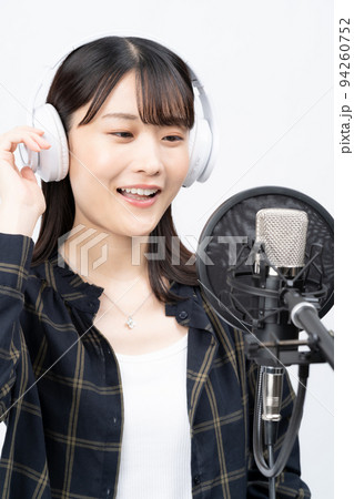 白いヘッドホンを付けて歌う若い女性 白いヘッドホンを付けて歌う若い女性 94260752