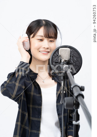 白いヘッドホンを付けて歌う若い女性 94260753